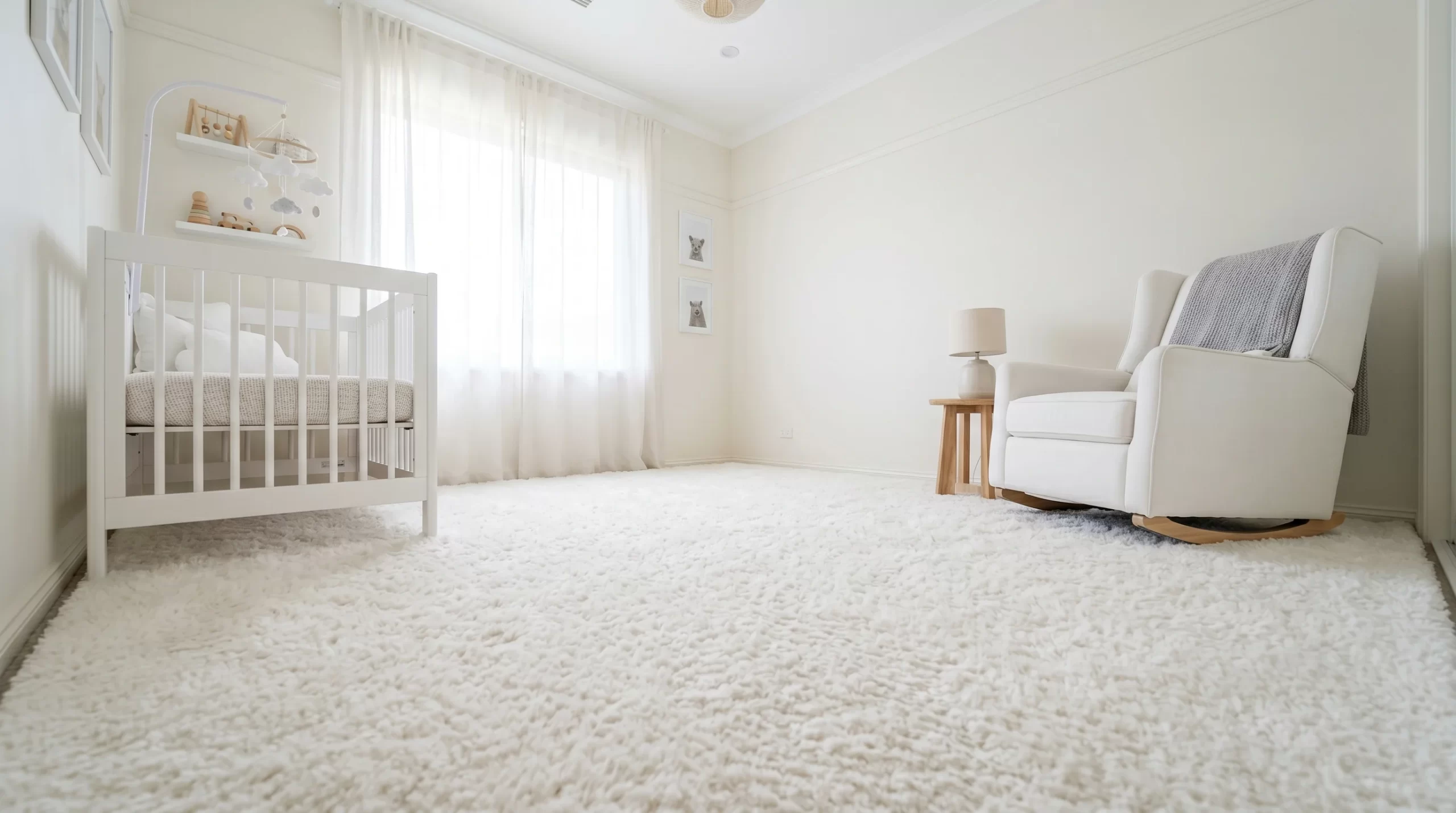 Clean nursery with white crib, rocking chair, and soft white rug